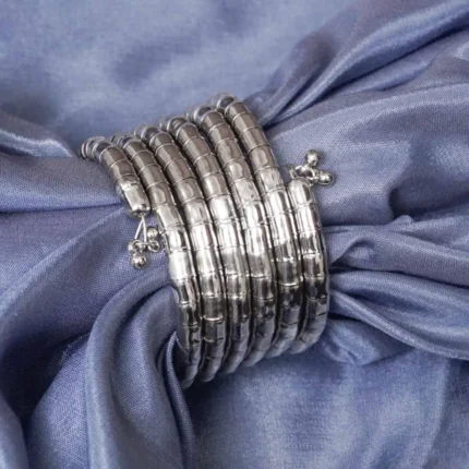 Contemporary metal spiral bracelet with a refined gold/silver texture, showcasing a multi-layered structure and bead details at both edges.