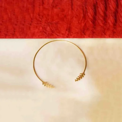 Sleek and sophisticated torque choker necklace in a brushed gold-tone finish, highlighted by hammered-textured leaf-shaped designs gracefully embellishing both ends