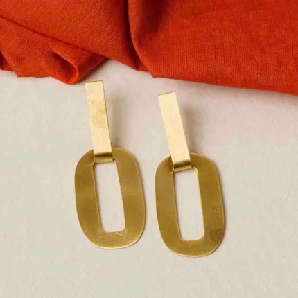 Modern brass drop earring with a sculptural design, showcasing an oval-shaped top with a hollow center, two i+CF300nterlinked hoops, and a textured triangle charm gracefully dangling at the bottom, secured with a push-back closure
