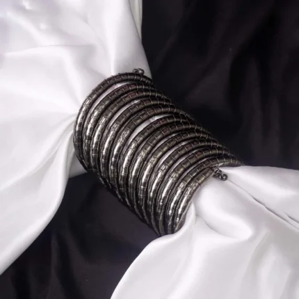 Contemporary metal spiral bracelet with a refined gold/silver texture, showcasing a multi-layered structure and bead details at both edges