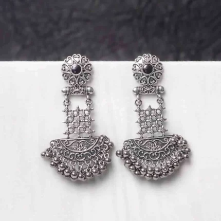 Traditional oxidized silver dangle earring featuring a finely crafted floral top detailing with gold-toned , elegant crescent shaped, and symmetrical geometric elements adorned with ghungroos at the end, and push back post.