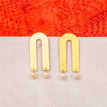 Minimalist arch-shaped brass earring with a smooth matte finish, adorned with two gracefully dangling pearls and a convenient push-back closure