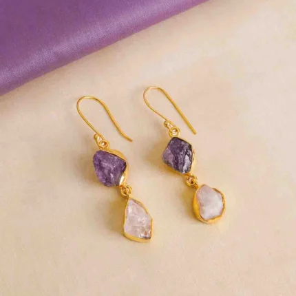 Modern asymmetrical teardrop-shaped metal dangle earrings with a gold tone and white/purple finish, featuring dual interconnected teardrop elements and raw gemstones with a soft shimmer, secured with a curved hook closure