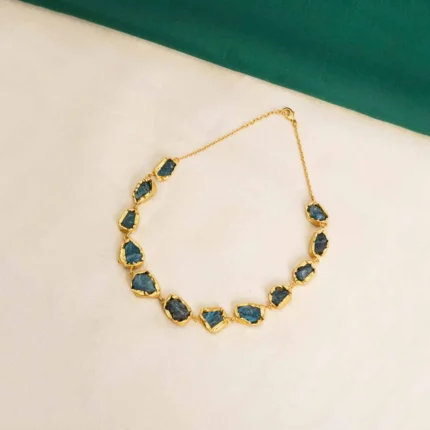 Flat cable chain choker necklace with a polished golden tone/emerald finish, featuring evenly spaced irregular organic-shaped purple raw gemstones and a lobster claw clasp