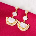 Statement geometric dangle earrings in a polished gold and pearl white finish, designed with a pearl top, an inverted square detail, a crescent-shaped base, and white enamel with pearl bead accents, completed with a push-back closure.