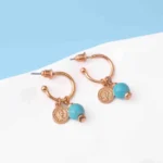 Trendy mini C-hoop earring with a polished gold-tone/turquoise finish, adorned with a turquoise bead and a small vintage-inspired coin charm, push-back post
