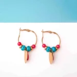Chic metal hoop earrings featuring a polished gold-tone finish, playful enamel accents, and dangling golden and red charm ,a push back for easy wear.