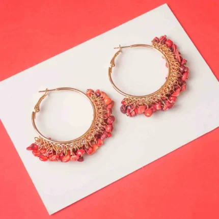 Chic metal hoop earrings featuring a polished gold-tone finish, playful reddish orange stone beaded accents, and a hinged back for easy wear