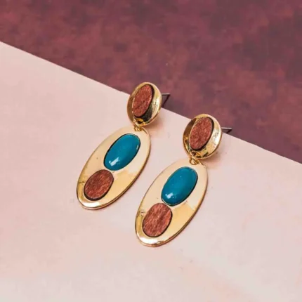 Eye-catching oval-shaped drop earrings with a luxe gold-tone finish, a deep teal stone at the center, and two organic wooden detailing, secured with a push-back post.