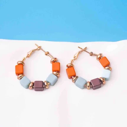 Chic metal hoop earrings featuring a polished golden-tone finish, /burnt umber,sky blue,coffee finish adorned with multicoloured square shaped beads with circular golden beads and a hinged back.