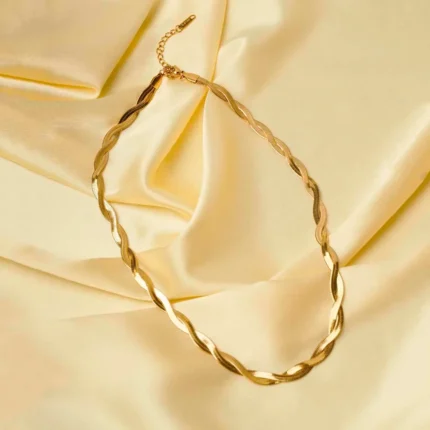 Sophisticated gold-tone snake chain necklace with a slightly irregular framed oval pendant, adorned with an embossed flower motif, complete with a lobster claw closure