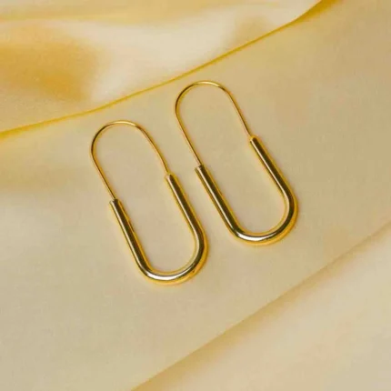 Refined gold-tone elongated oval metal hoop earrings with a pin structure and a lever back closure.