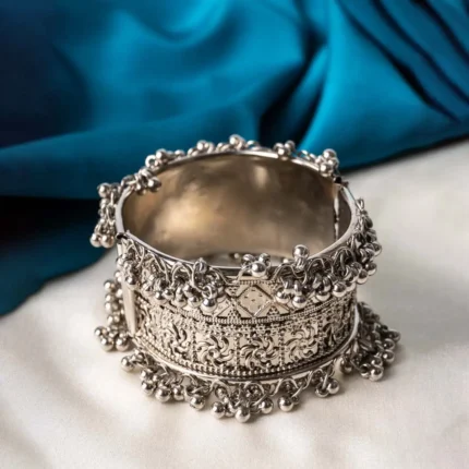 Oxidized silver-tone metal cuff bracelet featuring fine intricate detailing and adorned with ghungroos on both edges