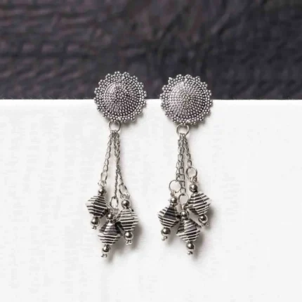 Traditional oxidized silver dangle earring featuring a finely crafted circular top, elegant chain tassels, and symmetrical geometric elements adorned with tiny bead accents