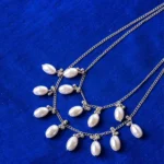 Chic double-layered curb chain necklace in a polished silver-tone finish, styled with oval pearls and small circular beads, complete with an S-hook closure.