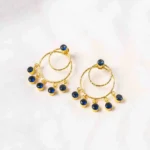 Trendy gold-tone/navy blue hoop earring with a hammered finish, layered hoop design, blue dangling circular beads, and a striking blue stone on top, fastened with a push-back closure.