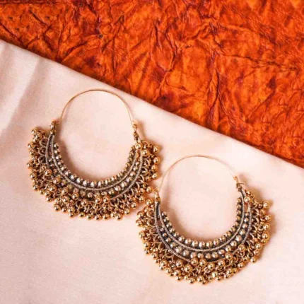 Ethnic metal drop earrings in an antique gold-tone finish, featuring a crescent design with fine bead detailing and dangling ghungroos, designed with a hinged back for secure wear.