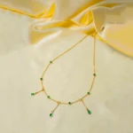 Stylish gold-tone necklace with a filled flat cable chain, an elegant teadrop shaped pendant,with delicate filigree and a green stone in the center and a lobster claw clasp