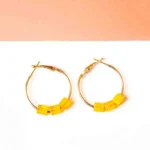 Chic metal hoop earrings featuring a polished golden-tone finish, playful three translucent yellow cube-shaped beads at the bottom , and a push back for easy wear.