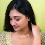 Modern three-tier curb chain necklace with a structured thick upper chain and two dainty lower chains, enhanced by multicolored beadwork and floral designs, secured with a lobster clasp