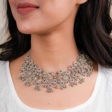 Timeless oxidized silver-tone curb chain necklace interconnected with small flower shaped designs adorned with colourful gemstones and and tiny ghungroos, finished with a sturdy S hook for a secure fit.