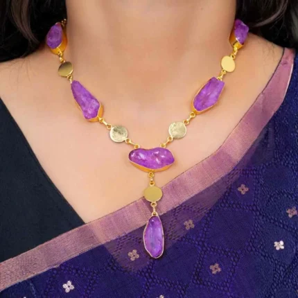 Modern brushed gold and purple curb chain necklace featuring free form raw gemstones, metallic disc details, and a lobster claw clasp for secure wear