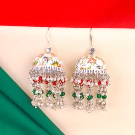 Fusion-style silver-tone jhumka earring featuring intricate floral meenakari artwork,fine chain tassels, and red and green pearl bead embellishments and a curved hook closure