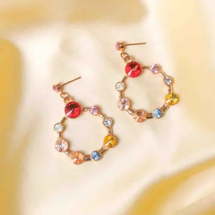 Chic metal hoop earrings featuring a polished golden-tone finish, playful round cage with gemstones, and a push back for easy wear.