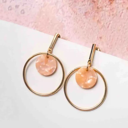 Chic metal hoop earrings featuring a polished golden-tone finish, playful round resin drop, and a push back for easy wear.