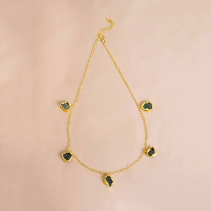 Sophisticated polished gold-tone curb chain necklace featuring shimmering emerald-green raw gemstones set in irregular teardrop designs, complete with an S-hook clasp.