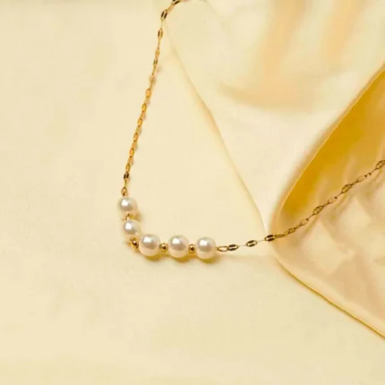 Elegant polished gold-tone sequin chain necklace featuring a graceful arrangement of pearls and golden mini beads at the center, finished with a lobster clasp.