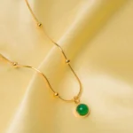 Dainty gold-tone satellite chain necklace designed with a glowy multicolored green gemstone pendant and lobster claw clasp