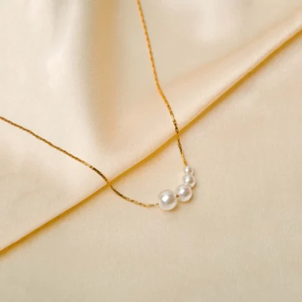Minimalist hayseed chain necklace with a gold-tone finish, showcasing five lustrous graduated pearl beads and a lobster claw closure.