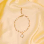 Elegant adjustable curb chain bracelet in a gold-tone finish, featuring a curved metallic wire centerpiece with a dangling spherical charm and a secure spring ring clasp.