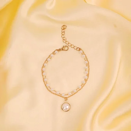 Elegant adjustable curb chain bracelet in a gold-tone finish, featuring a curved metallic wire centerpiece with a dangling spherical charm and a secure spring ring clasp.