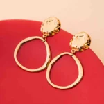 Chic asymmetrical circular earrings with a textured gold-tone disc, an organic finish, and a comfortable push-back fastening.