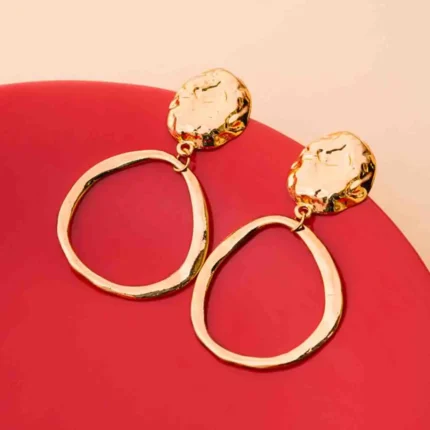 Chic asymmetrical circular earrings with a textured gold-tone disc, an organic finish, and a comfortable push-back fastening.