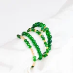 Pack of four green beaded bracelets, two with gold accents, one classic dark green and one with a butterfly charm,