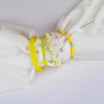 Pack of five yellow, clear, and shell disc beaded stretch bracelets.