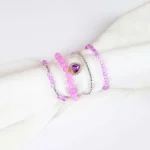 Pack of four beaded bracelets in lilac and silver tones. Each bracelet has a glossy or faceted finish and smooth elastic fit.