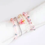 Pack of four pastel pink and clear glass beaded stretch bracelets, including a butterfly charm,