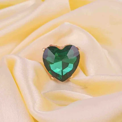 Cocktail ring featuring a faceted heart-shaped green stone in polished prong mount with filigree accents.