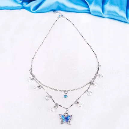 Double-layered silver necklace featuring a blue butterfly charm, adorned with pearl and crystal accents.