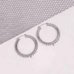 "Silver spiked hoop earrings with beaded edging, polished textured finish, and latch‑back closure. "
