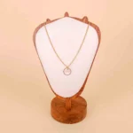 A delicate, gold-toned chain necklace featuring a single round pendant: a faux pearl suspended in the center of a thin, open, circular gold frame.