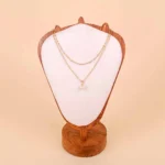 A delicate, gold-toned chain necklace featuring a single large, luminous faux pearl suspended as a simple drop pendant