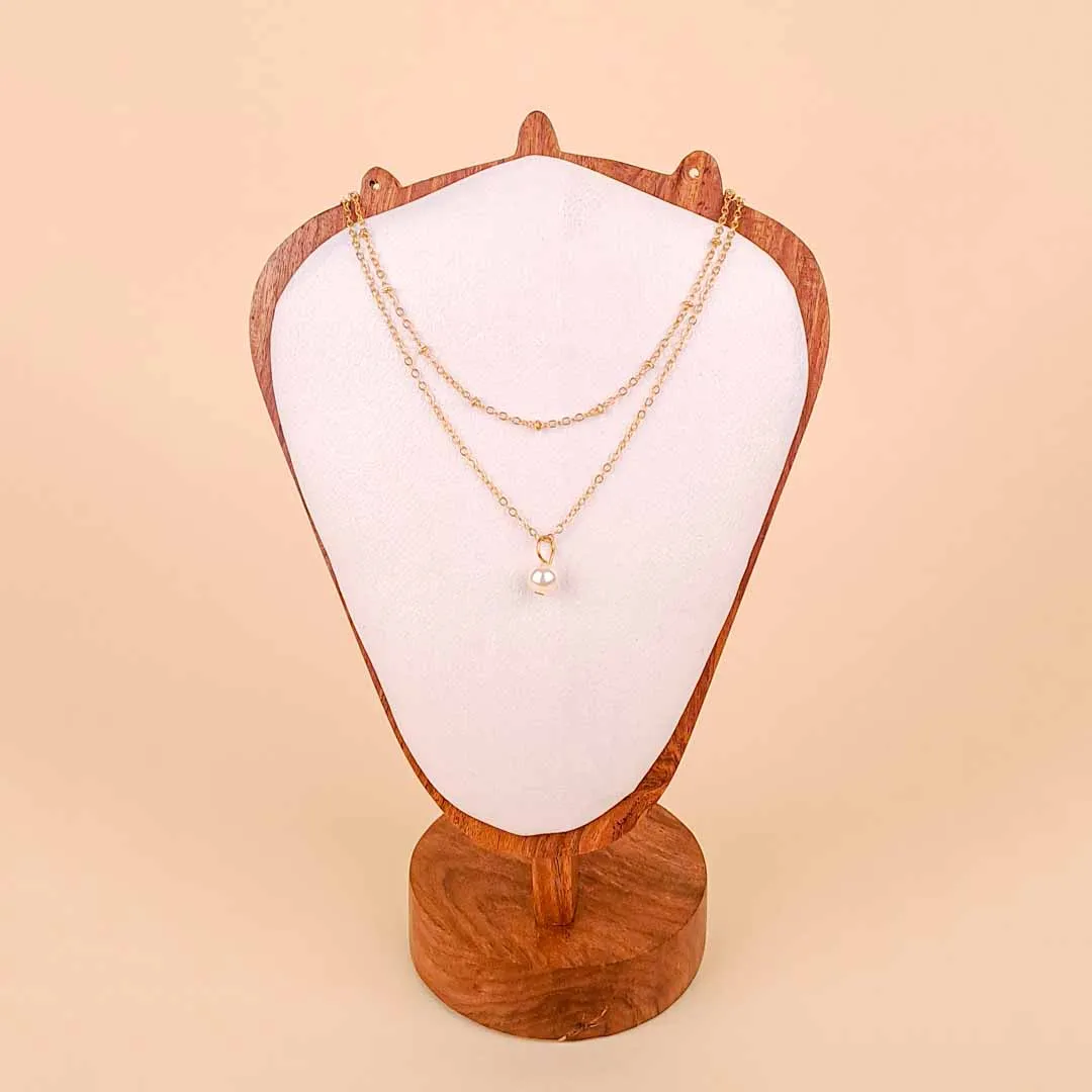 20251121_103110 (1) A delicate, gold-toned chain necklace featuring a single large, luminous faux pearl suspended as a simple drop pendant