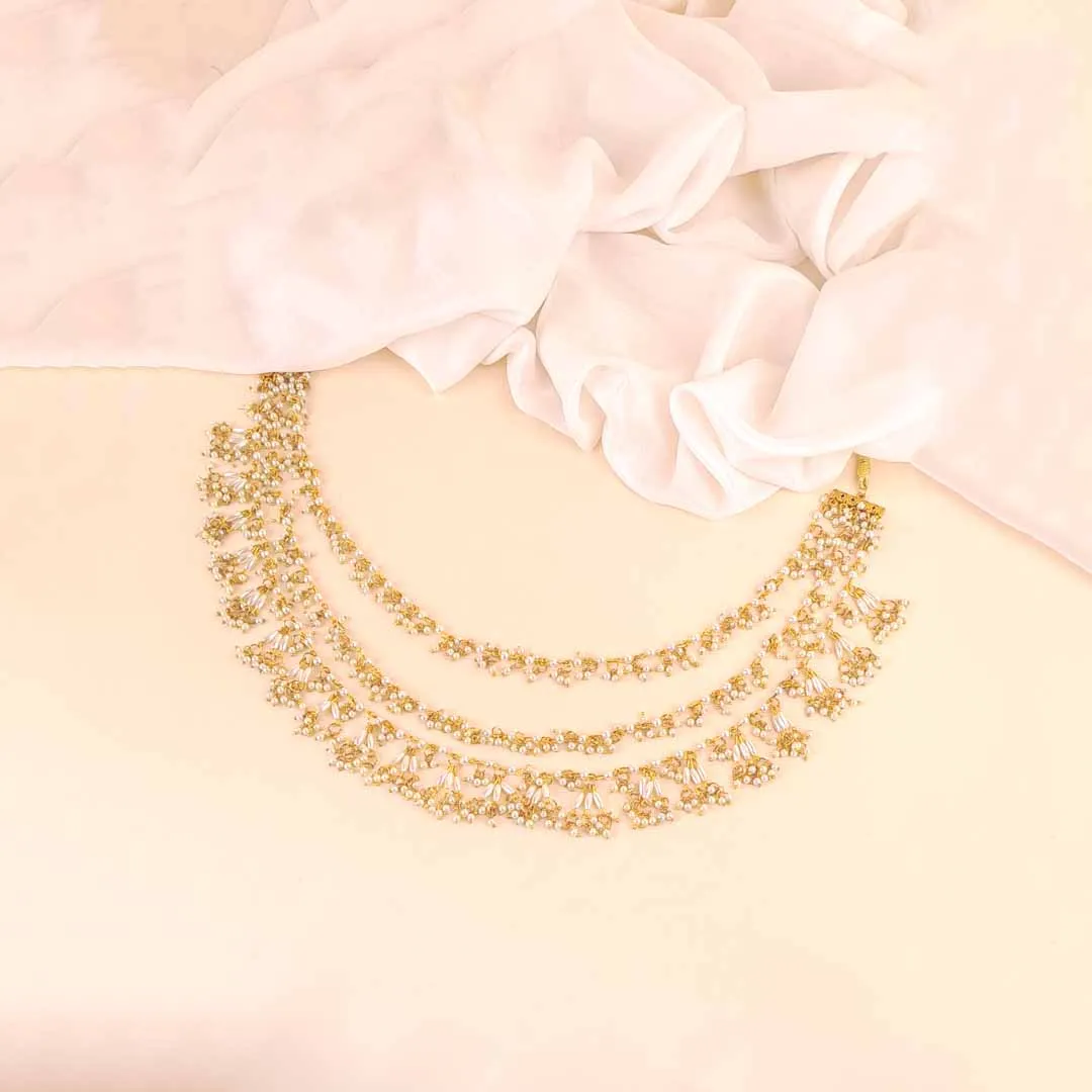 20251121_110416 (1) Three-tiered gold-tone necklace (Haar) featuring linked floral motifs with delicate white pearl beads cascading from the lower edge.