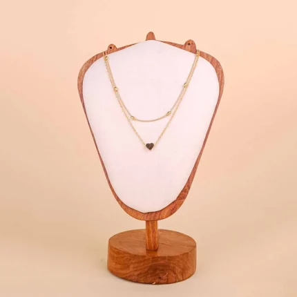 A delicate, gold-toned layered necklace featuring two integrated chains: a shorter chain with small, evenly spaced beads, and a longer chain with a small, polished heart-shaped pendant.