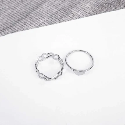 An open, adjustable silver-toned ring featuring a repeating, delicate pattern of interconnected heart shapes, another with heart in middle ideal for stacking.